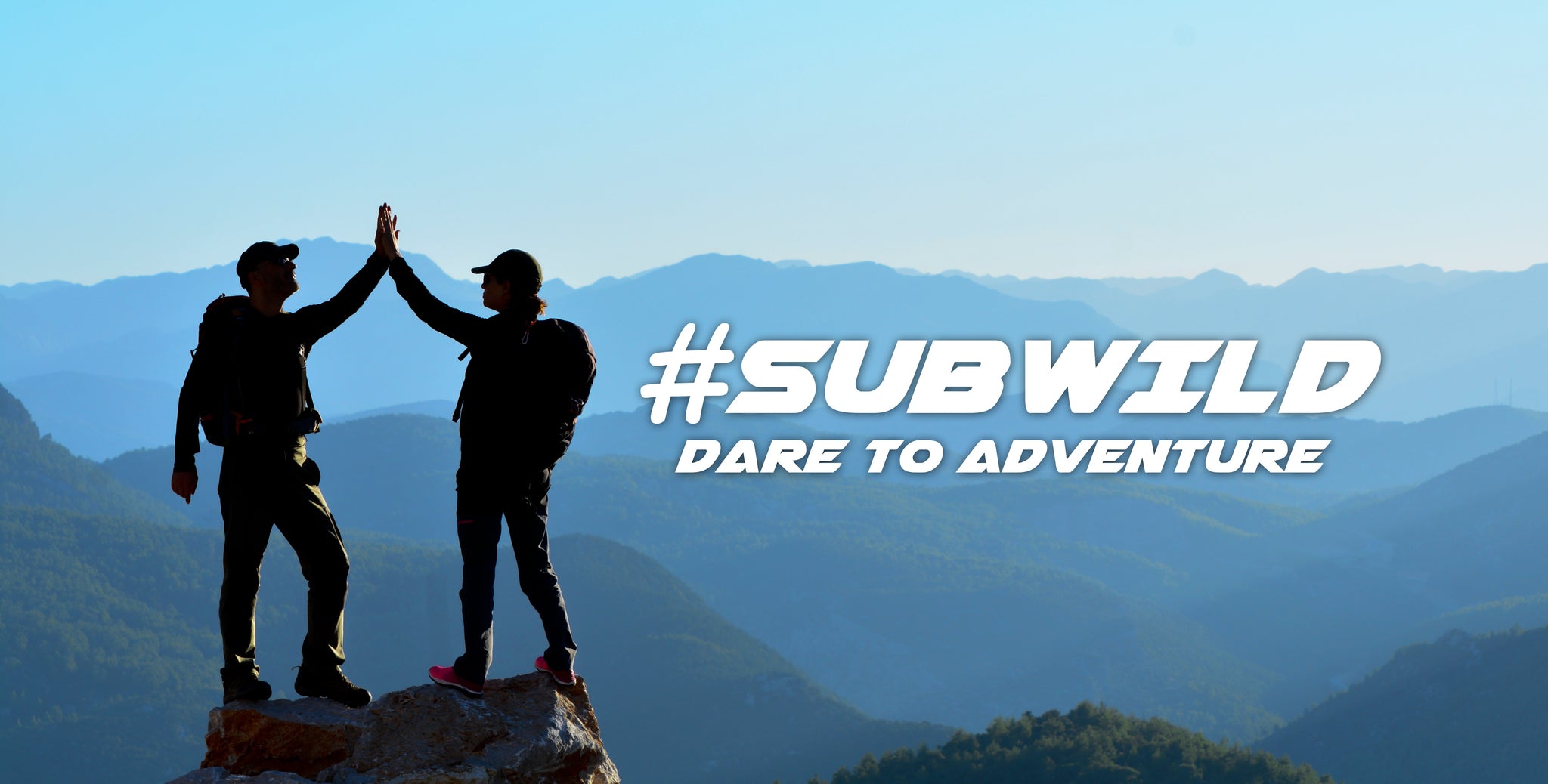 Subwild team wearing graphic tees as they high five on a rock.